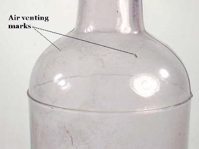 Air venting marks on an early 20th century liquor bottle; click to enlarge.