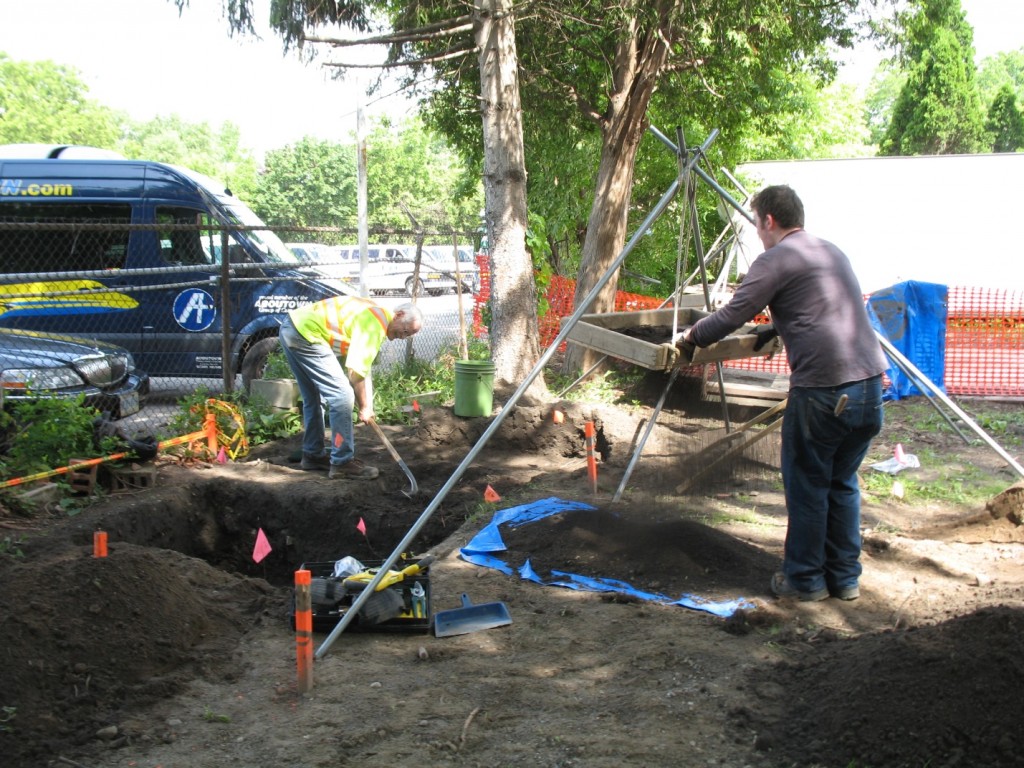 Two volunteers (Darryl Dann and Josh Dent), one digging and one standing at a screen, work at the Fugitive Slave Chapel Excavation