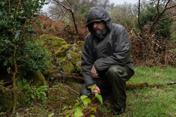 Person crouching down in a forested area.